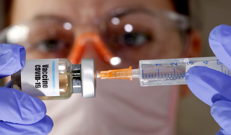 FILE PHOTO: A woman holds a small bottle labeled with a "Vaccine COVID-19" sticker and a medical syringe in this illustration taken April 10, 2020. REUTERS/Dado Ruvic/File Photo
