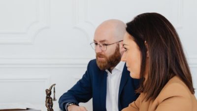 Man and woman discussing legal documents indoors, featuring Lady Justice statue.