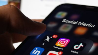 A person holding a smart phone with social media on the screen