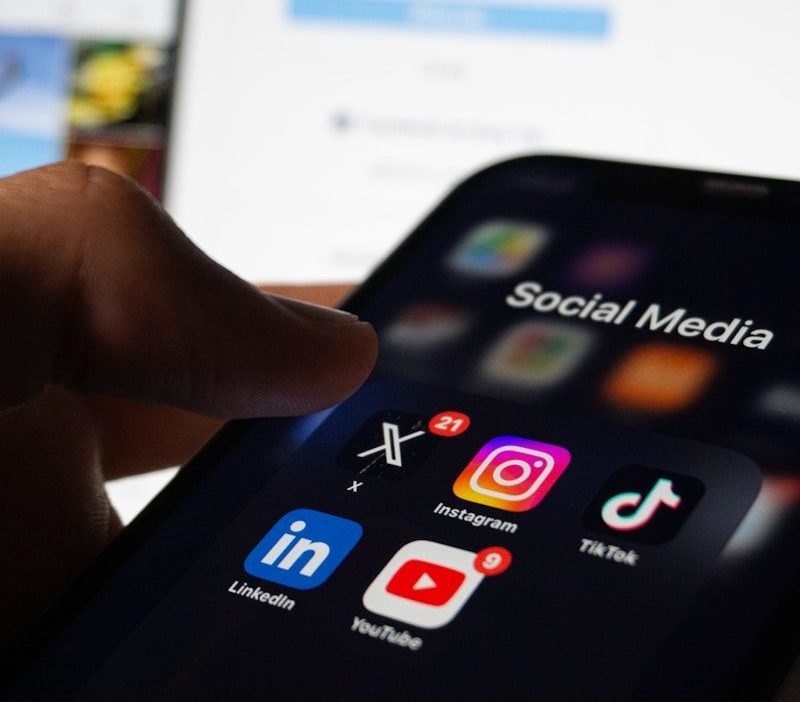 A person holding a smart phone with social media on the screen