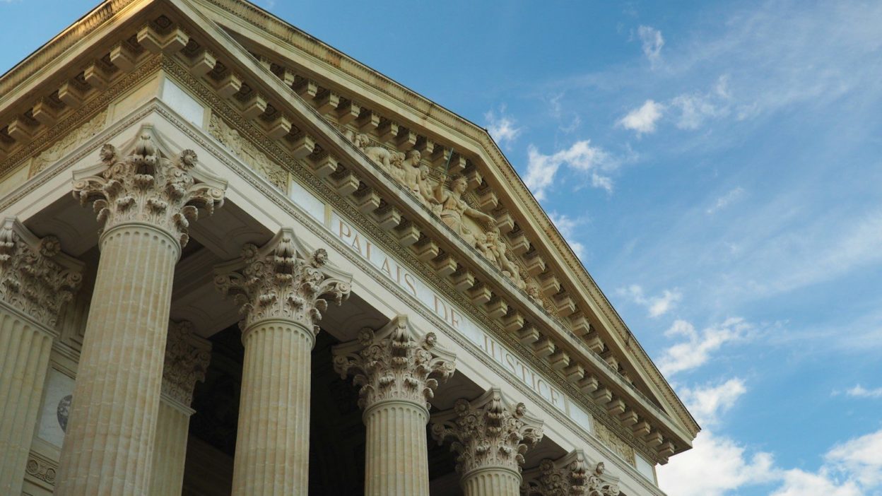 a tall building with columns and a sky background